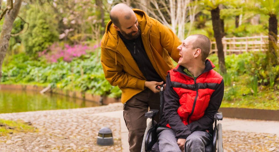 The caregiver pushing young man in wheelchair