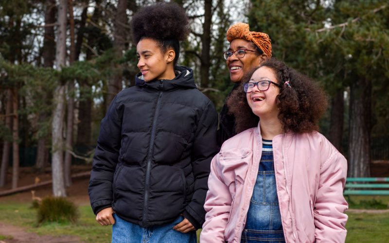 Caregiver with two young women outdoors