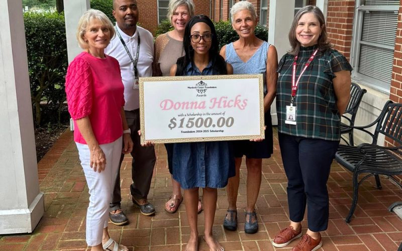 Scholarship award winner holding large check with members of the Murdoch Center Foundation